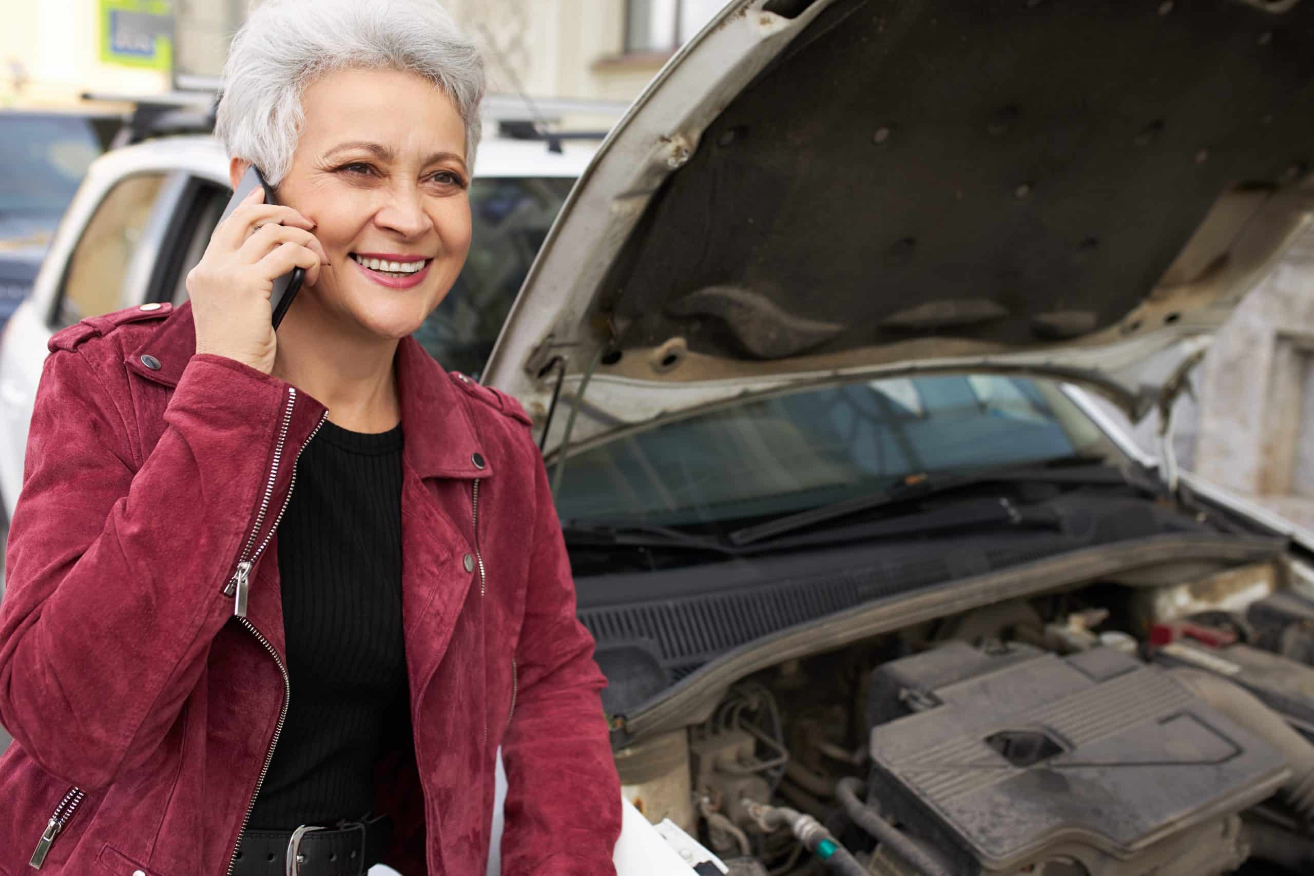 Female driver standing near her broken scrap car